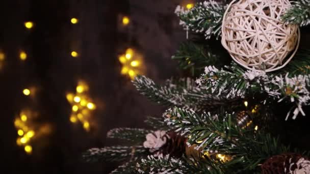 滑らかなカメラの動き 選択的な焦点 クリスマスツリーの枝の暗い部分でのクローズアップ ボケの光の背景 — ストック動画