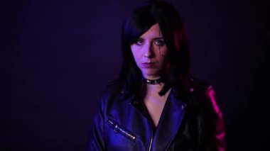 Siyah deri ceketli, elinde katana olan, mavi ve mor arka fonda izole bir şekilde poz veren kısa saçlı genç bir kadının portresi, siber punk konsepti..