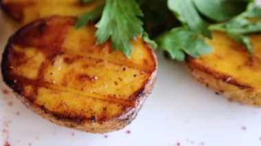 Yakın plan fırında patates, yeşil maydanozlu beyaz tabak, düz kamera hareketi, seçici odaklanma..