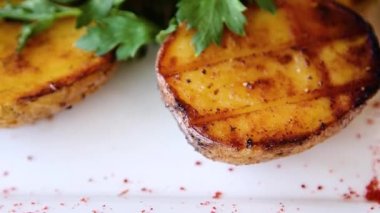 Yakın plan fırında patates, yeşil maydanozlu beyaz tabak, düz kamera hareketi, seçici odaklanma..