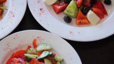 Pürüzsüz kamera hareketi, seçici odaklanma, siyah ahşap bir masada sebze salatalarıyla bir tabağın yakın çekimi..