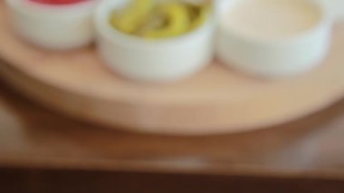 Pürüzsüz kamera hareketi, seçici odak noktası Bokeh 'ten, yuvarlak ahşap tepside beyaz kaselerdeki sos çeşitlerinin yakın çekimi..