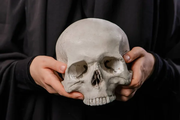 黒い衣を着た女性の手に人間の頭蓋骨が — ストック写真