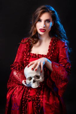 Rokoko döneminde kırmızı elbiseli genç ve çekici bir kadının portresi. Elinde kafatası, mavi arka planda izole bir şekilde poz veriyor..