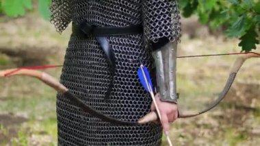 Pürüzsüz kamera hareketi, seçici odaklanma, zincirli bir kadın portresi ve elinde bir yayla bir yaz ormanı zemininde duran diş telleri..