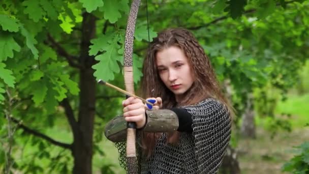 滑らかなカメラの動き 選択的な焦点 鎖状のメールとブラジャーの若い女性の肖像画は 夏の森を背景に 弓を目指している — ストック動画