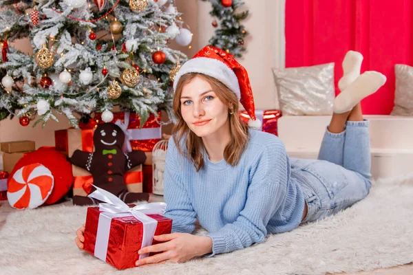 Egy Fiatal Vonzó Egy Ajándékkal Kezében Fekszik Egy Karácsonyfa Szilveszteri — Stock Fotó