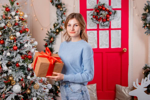 Egy Fiatal Portréja Egy Ajándékkal Kezében Egy Karácsonyfa Hátterében — Stock Fotó