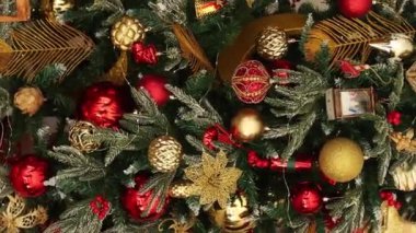 Dikey video, düz kamera hareketi, Noel oyuncaklarına yakın çekim, köknar dalları, dekorasyonlar, seçici odaklanma. Bokeh dolusu çelenk..