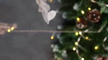 Dikey video, düz kamera hareketi, Noel oyuncaklarına yakın çekim, köknar dalları, dekorasyonlar, seçici odaklanma. Bokeh dolusu çelenk..