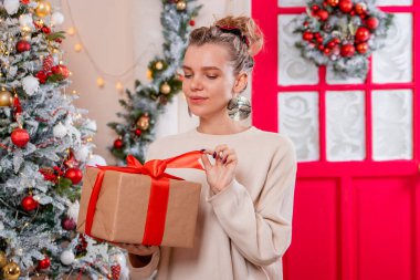 Bir Noel ağacının arka planında elinde hediyeyle genç bir kadının portresi..