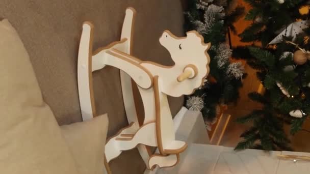 縦のビデオ クリスマスツリーの背景に対する子供の木製のロッキング馬 滑らかなカメラの動き 選択的な焦点 — ストック動画