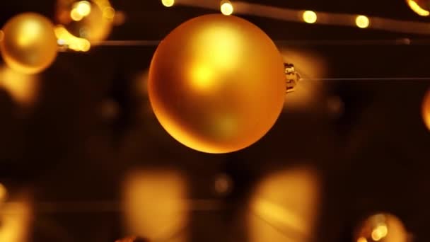 垂直录像 挂在花环背景上的金色圣诞球 相机运动 选择性焦距 — 图库视频影像