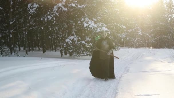 一个戴着角形头盔 钢制胸牌和带着双手斧头的铁链邮件的中世纪幻想战士 在夕阳西下走过冬季的森林 有选择的重点 — 图库视频影像