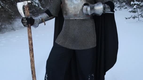 中世のファンタジーの戦士 角のヘルメットとチェーンメール 彼の手で両手の斧は 冬の森でプレートグローブで鋼の胸に自分自身を打つ サウンドによるビデオ — ストック動画