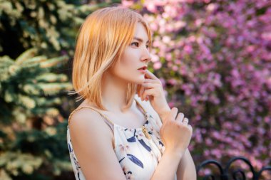 Sakura çiçeklerinin arka planında poz veren çekici bir kadının portresi..