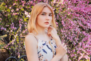 Sakura çiçeklerinin arka planında poz veren çekici bir kadının portresi..