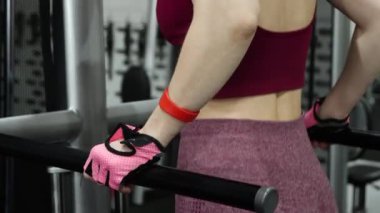Spor salonundaki paralel barlara triseps daldırmak için egzersiz yapan genç atletik kadın, seçici odaklanma, kamera hareketi.