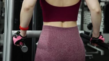Spor salonundaki paralel barlara triseps daldırmak için egzersiz yapan genç atletik kadın, seçici odaklanma, kamera hareketi.
