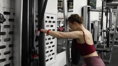 Genç atletik çekici kadın spor salonundaki egzersiz makinesinde egzersiz yapıyor. Seçici odak, kamera hareketi.