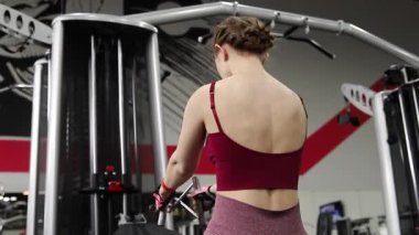Spor salonundaki bir makinede onu çalıştırmak için egzersiz yapan atletik genç bir kadın. Seçici odak, kamera hareketi.