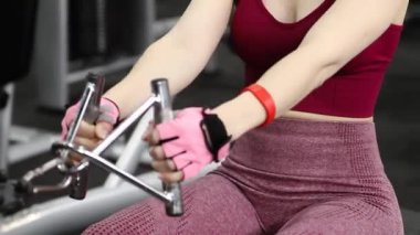Spor salonundaki bir makinede onu çalıştırmak için egzersiz yapan atletik genç bir kadın. Seçici odak, kamera hareketi.