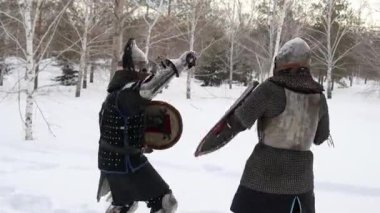 İki ortaçağ savaşçısının savaşı. Bir şövalye ve Orta Asya savaşçısı kış ormanında savaşıyor..