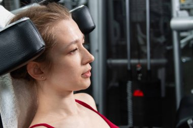 Genç, atletik bir kadın spor salonundaki bir makineye bacak presi yapıyor, bacaklarını çalıştırmak için..