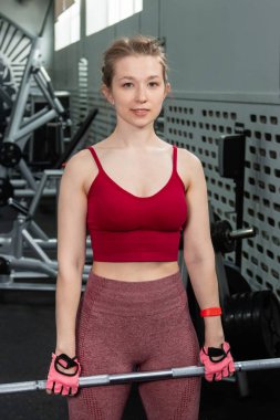 Genç bir atletik kadın spor salonunda halterle ağırlık kaldırma, sırt ve bacak antrenmanı yapıyor..