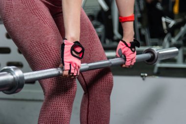 Genç bir atletik kadın spor salonunda halterle ağırlık kaldırma, sırt ve bacak antrenmanı yapıyor..