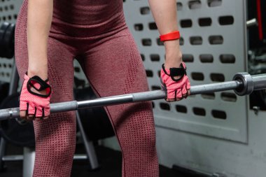 Genç bir atletik kadın spor salonunda halterle ağırlık kaldırma, sırt ve bacak antrenmanı yapıyor..