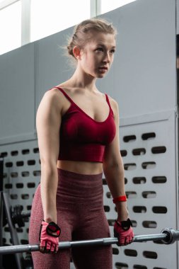 Genç bir atletik kadın spor salonunda halterle ağırlık kaldırma, sırt ve bacak antrenmanı yapıyor..