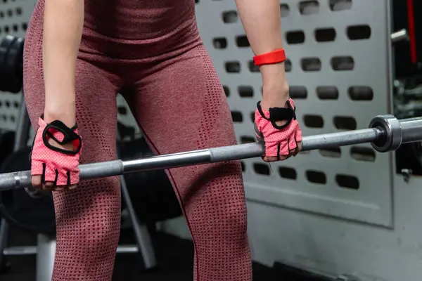 Genç bir atletik kadın spor salonunda halterle ağırlık kaldırma, sırt ve bacak antrenmanı yapıyor..