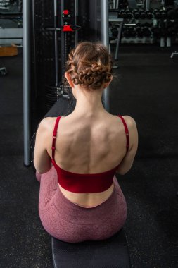 Sporcu genç bir kadın spor salonundaki bir makinede onu eğitmek için egzersiz yapıyor..