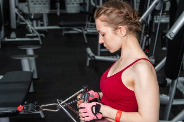 Sporcu genç bir kadın spor salonundaki bir makinede onu eğitmek için egzersiz yapıyor..