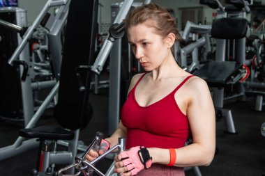 Sporcu genç bir kadın spor salonundaki bir makinede onu eğitmek için egzersiz yapıyor..