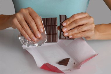 Koyu renkli çikolata paketini açan ve kıran bir kadın...