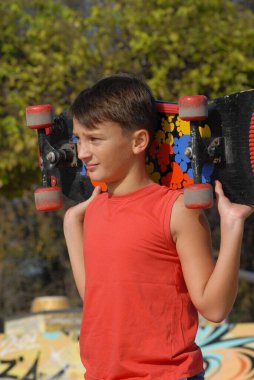 Kaykaycı çocuk şehir parkında kaykay yapıyor.