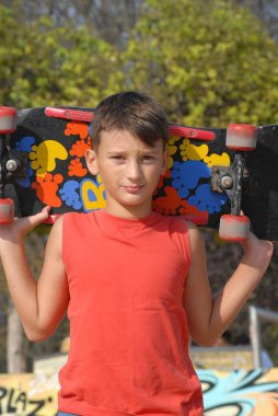 Kaykaycı çocuk şehir parkında kaykay yapıyor.