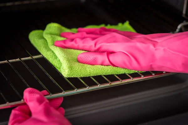 stock image Cleaning the oven. Woman's hand in pink gloves cleans oven inside. Clean oven in kitchen.