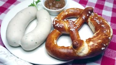 İki Münih beyaz sosisi, simit ve tatlı Bavyera hardalı, tabakta dönüyor.