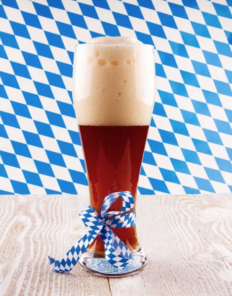 在巴伐利亚图案背景的玻璃杯中的黑麦啤酒 高质量的照片 — 图库照片