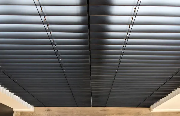 stock image Top view of wooden venetian blinds, black color, on the full height window. Natural blinds create a great look, perfectly balancing privacy and light control. Semi-closed blinds at a certain angle.