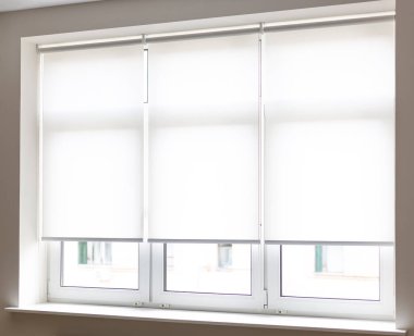 Bright roller shades are neatly installed on white-framed windows, allowing soft daylight to filter through. The room is minimalistic and well-lit, enhancing the serene atmosphere. clipart