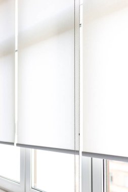 Gündüz vakti parlak, minimalist bir odada modern beyaz patenler pencereleri zarifçe kapatıyor. Zincir mekanizması yakın çekim ile paten panjurları.