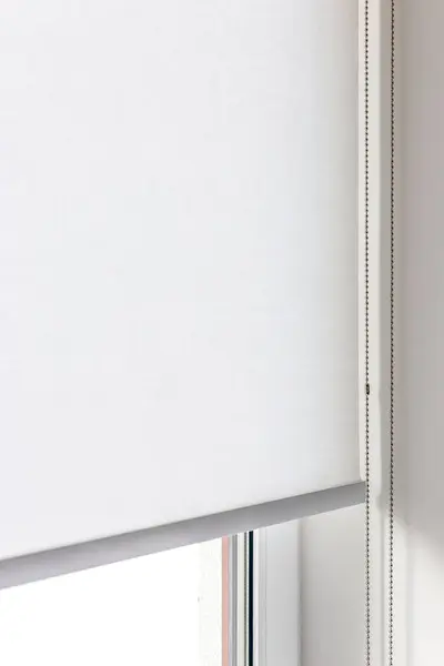 Penceredeki beyaz perdenin detaylı görüntüsü. Metal zincir kontrollü güneş kremi perdesi..