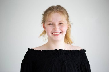 Sarı saçlı mutlu genç bir kadın, omuzlarından siyah bir bluzla doğal güzelliğini sergiliyor. Yumuşak, hafif zemin, genç yetişkin neşeli mizacını geliştirir..