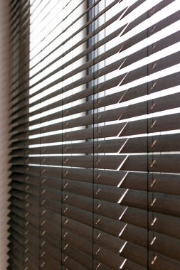 Bu resim, pencereye takılmış şık ve zarif ahşap panjurlar sergiliyor. Tahta panjurlar iç dekora doğal ve şık bir dokunuş ekleyerek hem ışık hem de mahremiyet sağlar..