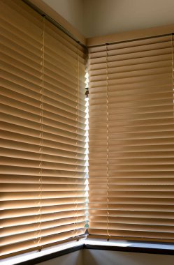 Ahşap panjurlar, hafif ışıklandırılmış bir iç mekanda köşedeki pencereleri kapatarak mahremiyet ve güneş ışığını dağıtıyor. Yatay kirişler odaya sıcaklık ve doku katıyor. Şehirde eko yaşam.