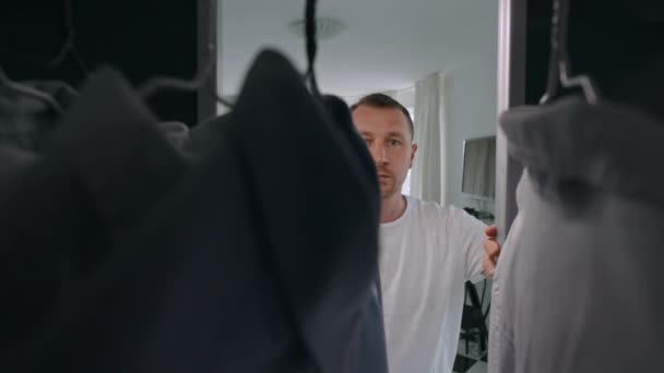 Мужчина Открывающий Двери Гардероба Выбирает Рубашку Утром Квартире Большими Окнами — стоковое видео